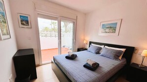 A bedroom with a bed, a nightstand, a lamp, and a view of the outside. - 3 Bedroom Apartment on Golf Resort with Pool (Alhama de Murcia)
