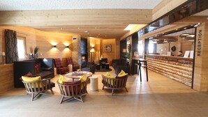 A cozy, wood-paneled interior with a reception desk, seating area, and a fireplace. - Apartment in Les Menuires With Spa & Pool (Les Belleville)