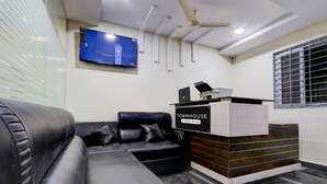 Una moderna zona de recepción con un sofá de cuero, un televisor de pantalla plana montado en la pared y un mostrador de recepción que dice "TOWNHOUSE".