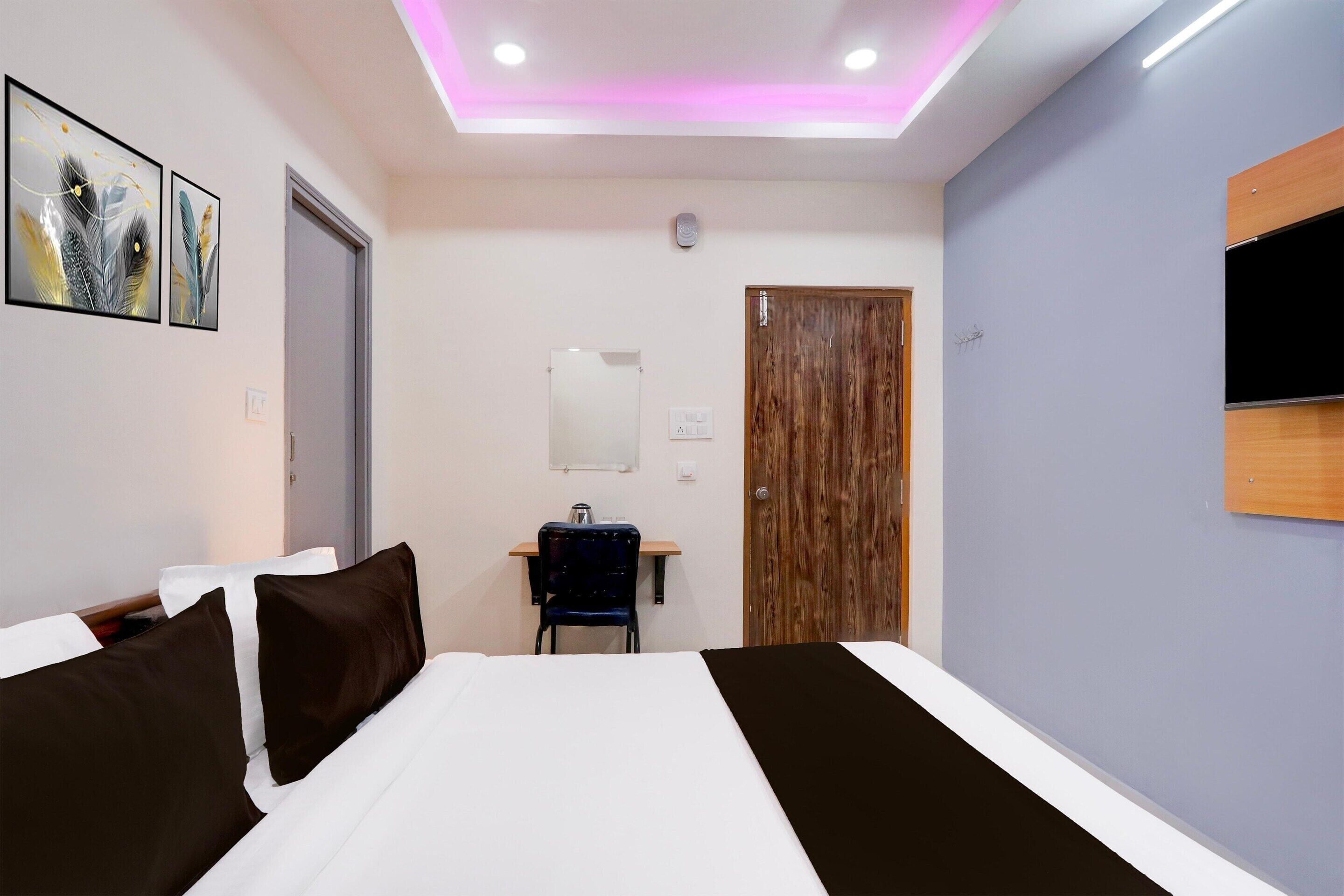A hotel room with a bed, a desk, a chair, and a TV mounted on the wall.