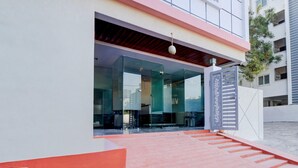Un edificio moderno con acceso de vidrio, una rampa roja que conduce al acceso, y un portón decorativo.