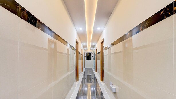Un pasillo moderno de hotel con un piso de mármol brillante, iluminación empotrada y vistas a una habitación al fondo.