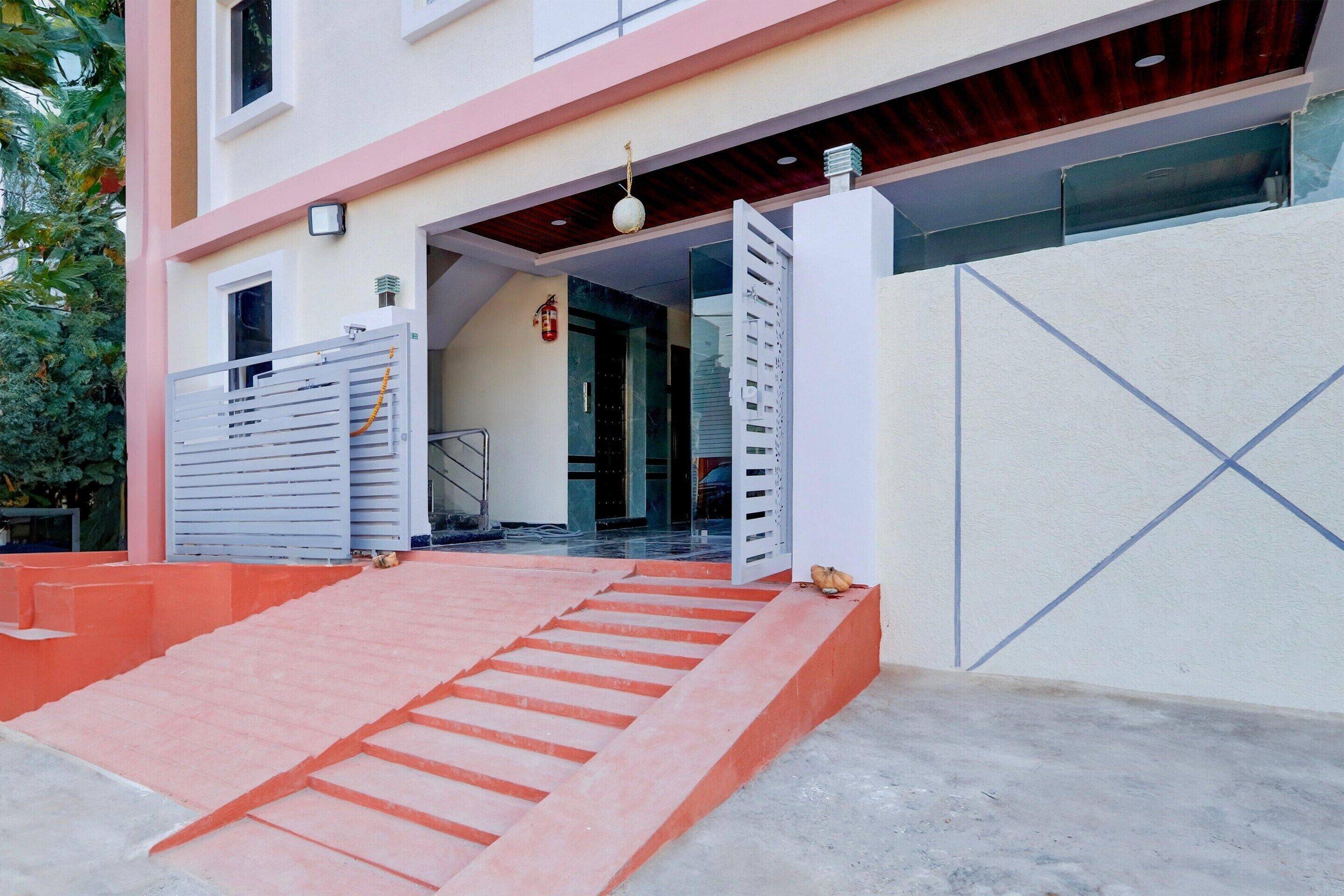 A building entrance with a staircase leading up to a door, a fire extinguisher, and a metal gate.