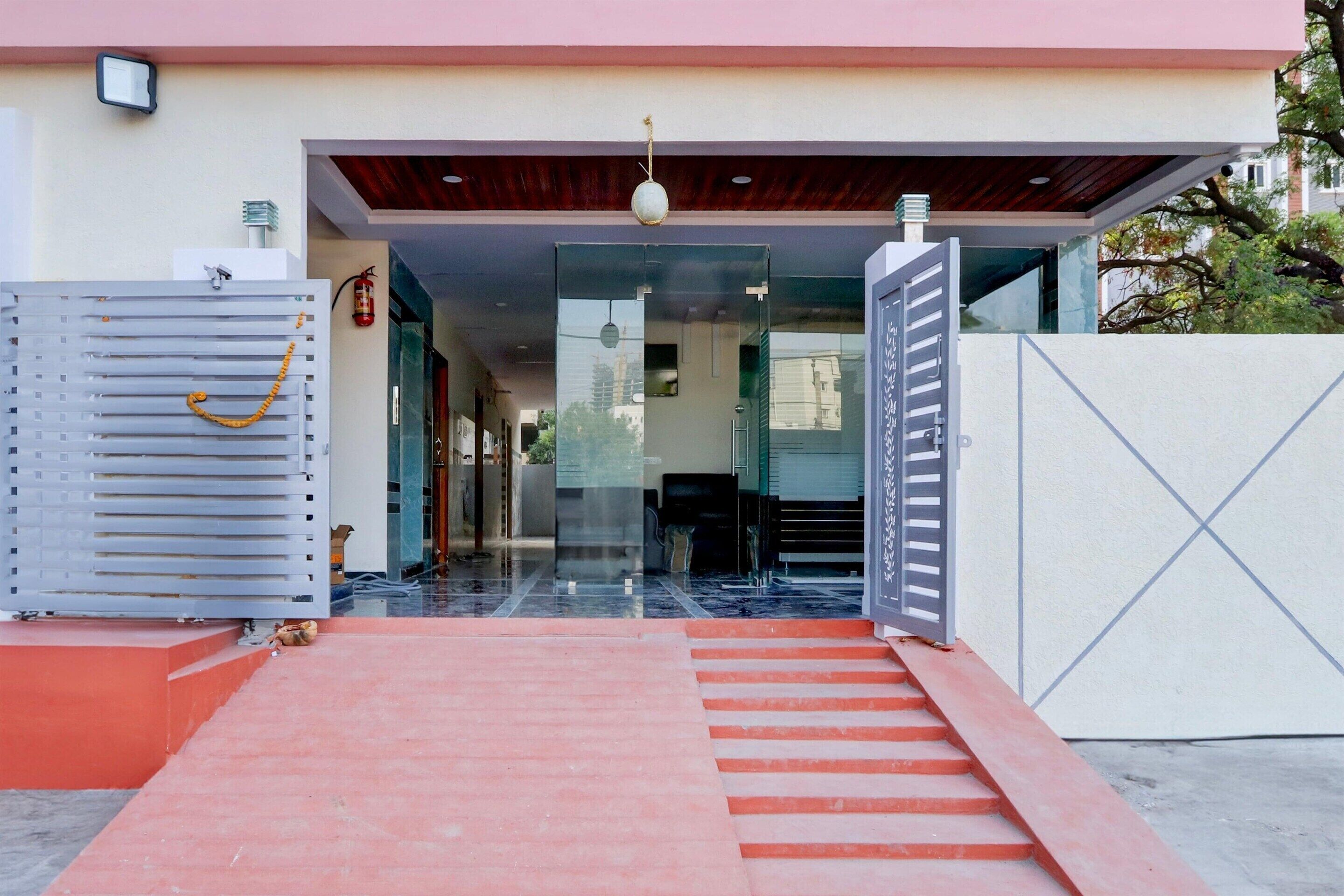 A modern building entrance with a red carpet leading to a glass door.