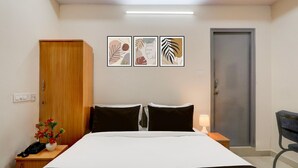Una habitación de hotel con una cama, mesita de noche, lámpara y un armario de madera.