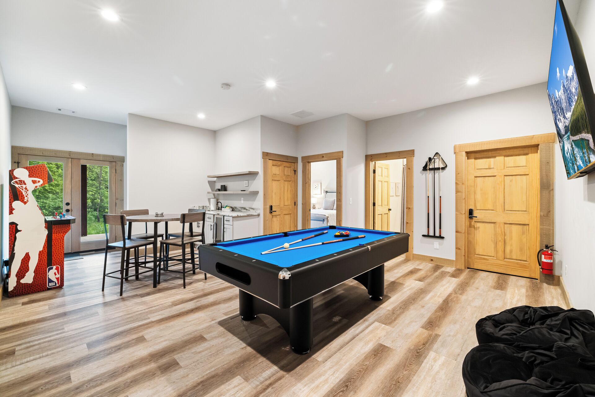 A modern indoor recreational area with a pool table, seating, and a basketball arcade.