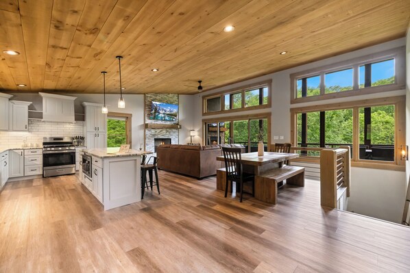 A spacious kitchen with wooden cabinets, a central island, and a stone fireplace.