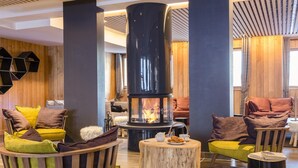 A cozy lounge area with a central wood-burning stove, comfortable seating, and a wooden wall. - Apartment in Tignes With Ski-in/ski-out Access (Tignes)