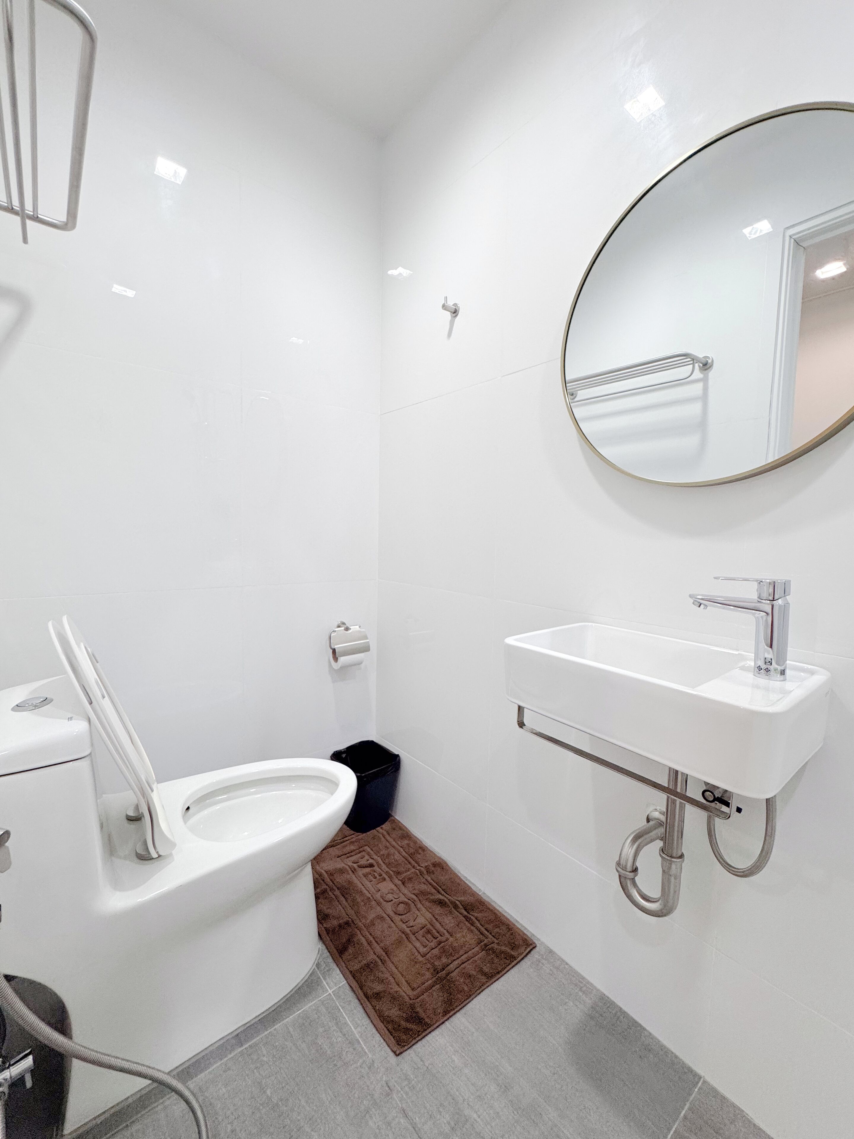 A modern bathroom with a toilet, bidet, sink, and mirror.