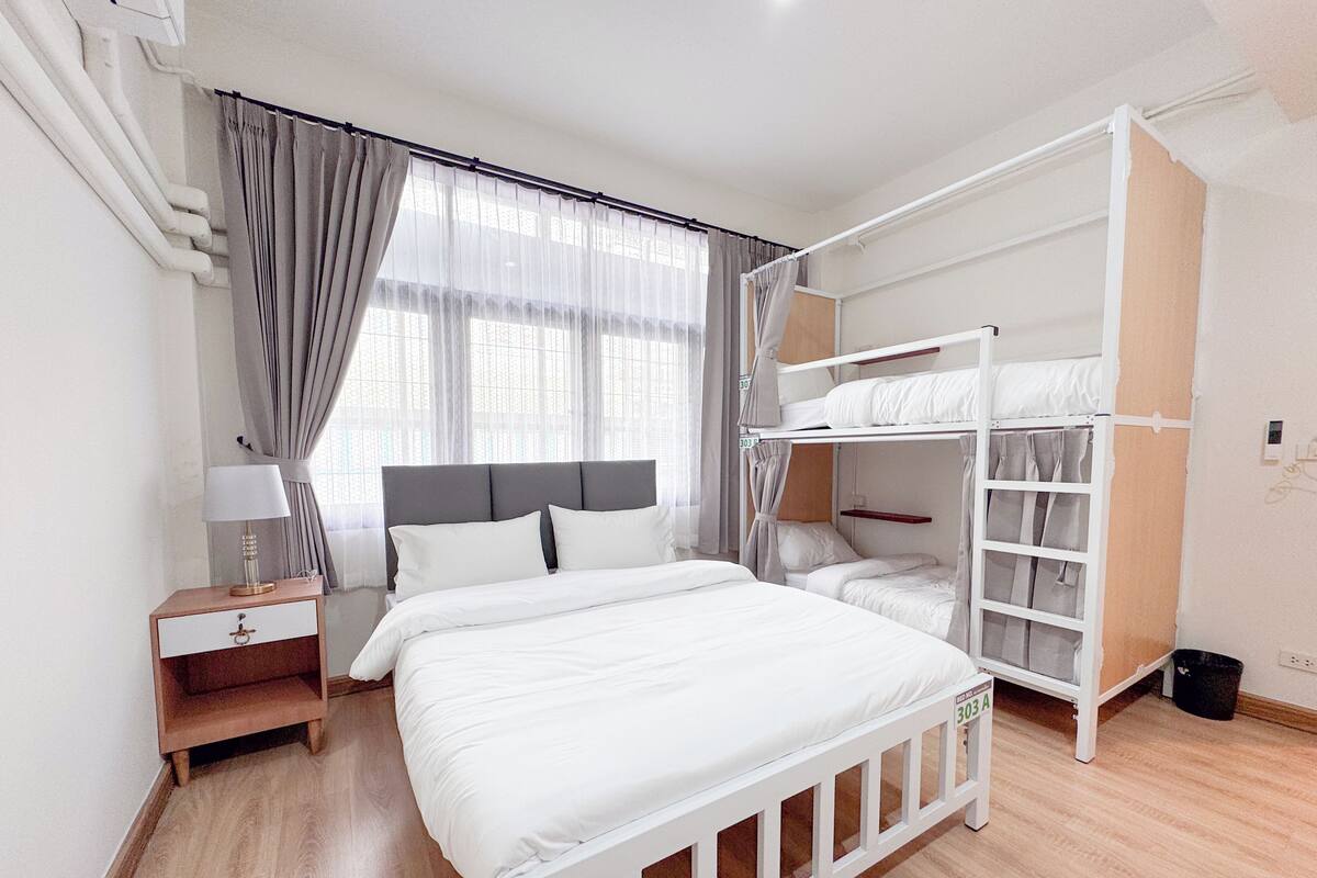 A bedroom with a bunk bed, a bedside table with a lamp, and a wardrobe with hanging space.