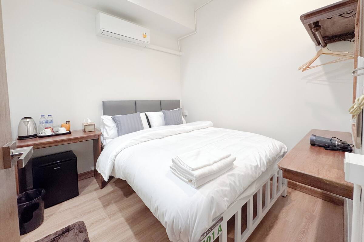 A neatly arranged bedroom with a bed, bedside table, and an air conditioning unit.