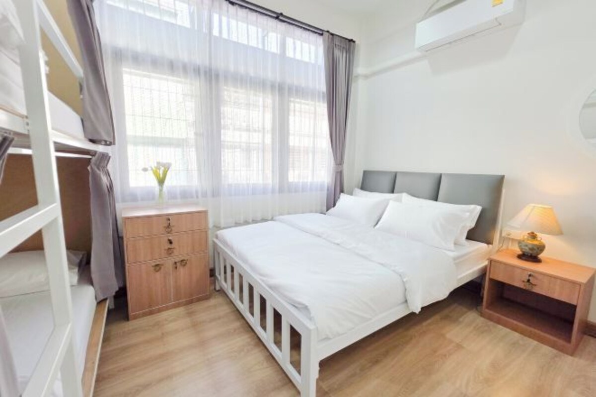 A bedroom with a bed, a nightstand, a dresser, and a window with curtains.