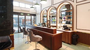 Un área de bar moderna con mostrador de madera, taburetes y luminarias colgantes.