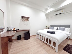 A modern bedroom with a white bed, grey headboard, and a wooden desk with a mirror. - Vintana Siam Hotel Bangkok (Bangkok)