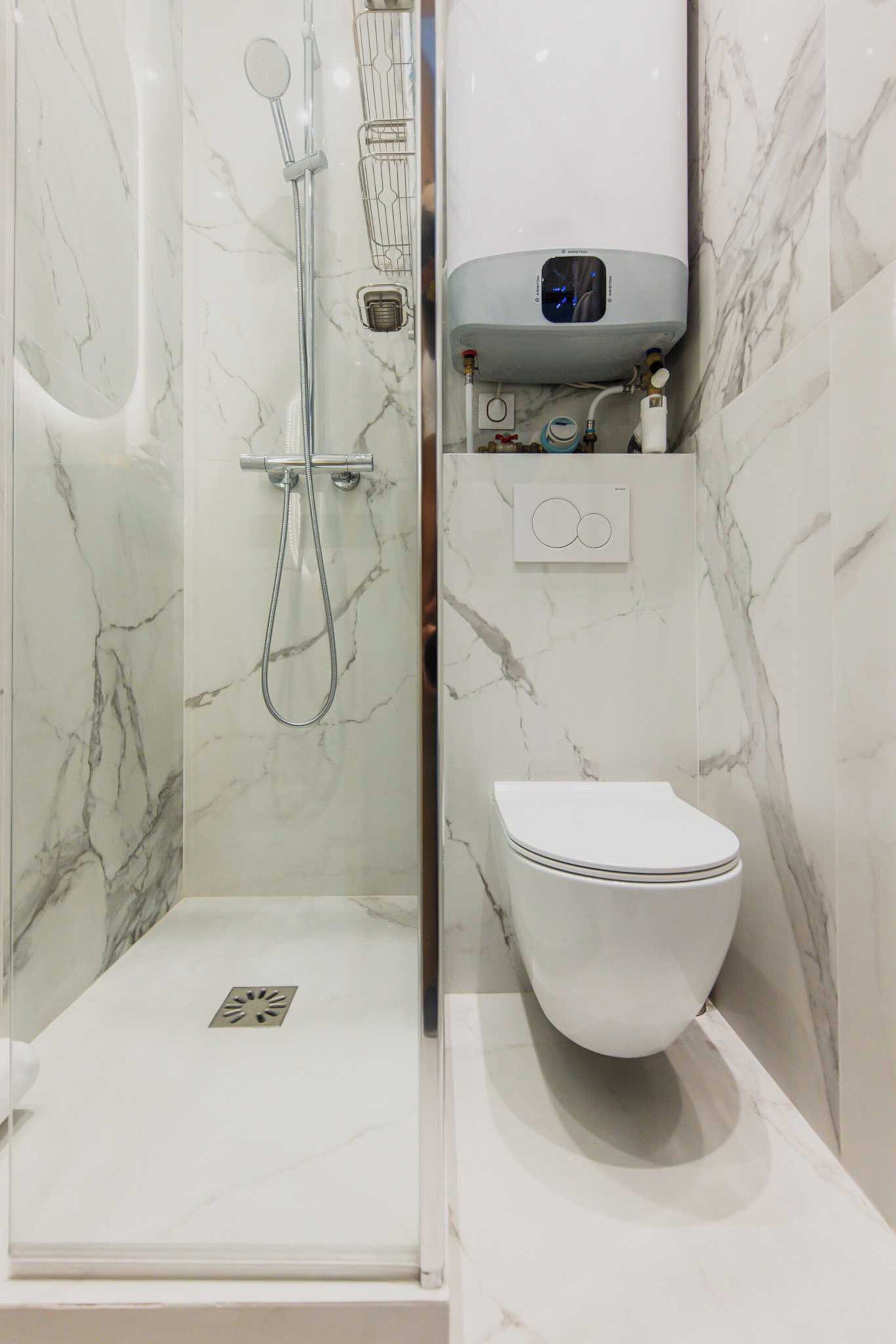 Une salle de bain moderne équipée d’une douche, de toilettes et d’un chauffe-eau intégré.