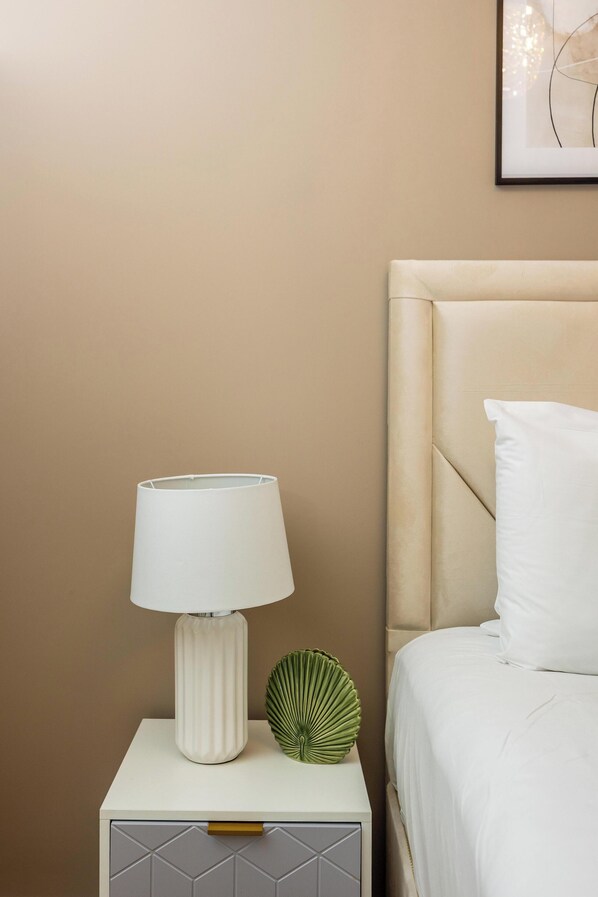 A neatly made bed with a white pillow and a beige headboard.