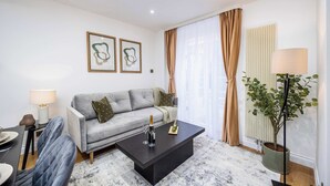 A modern living room with a grey sofa, a black coffee table, and a potted plant. - Modern 4 Bed Flat | Prime Central London Location (Greater London)