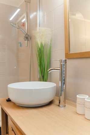 A bathroom with a white sink, a shower, and a mirror.
