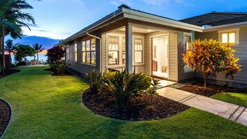 Une maison moderne dotée d’un porche abrité, d’une pelouse bien entretenue et d’un petit jardin.