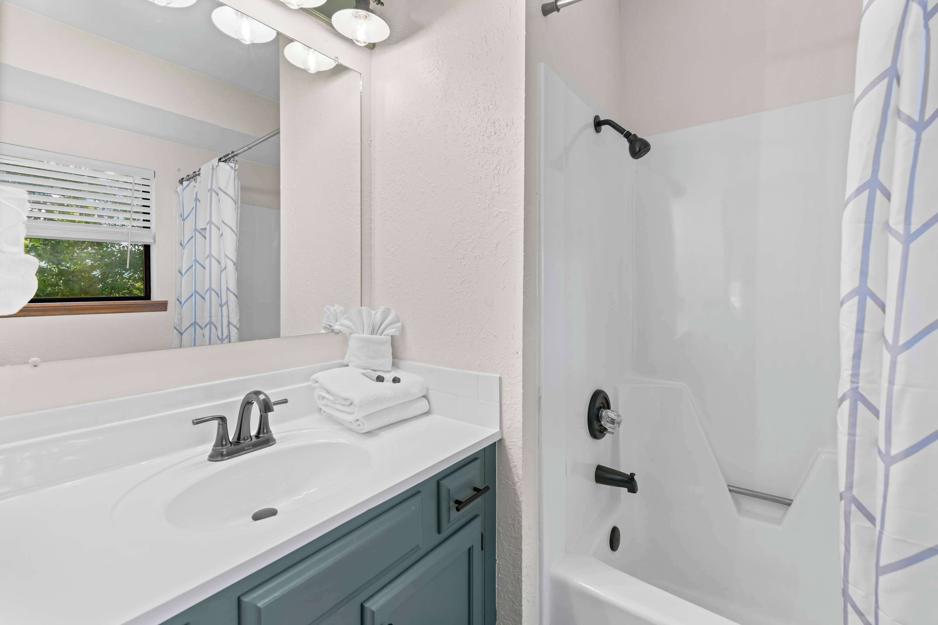 A bathroom with a white sink, a mirror, a towel rack, and a shower area.