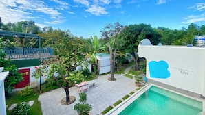 Un espace piscine aménagé sur le toit, avec un ciel d’un bleu limpide, un mur blanc orné d’un motif bleu en forme de cœur et un banc.