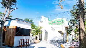 Un espace extérieur aménagé en terrasse, avec un bar, des sièges et une fresque murale.