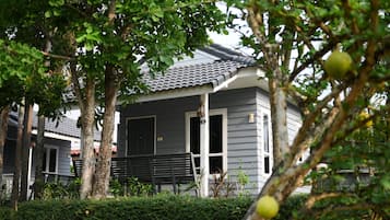 A house with a grey exterior, a tiled roof, and a front porch with a bench.