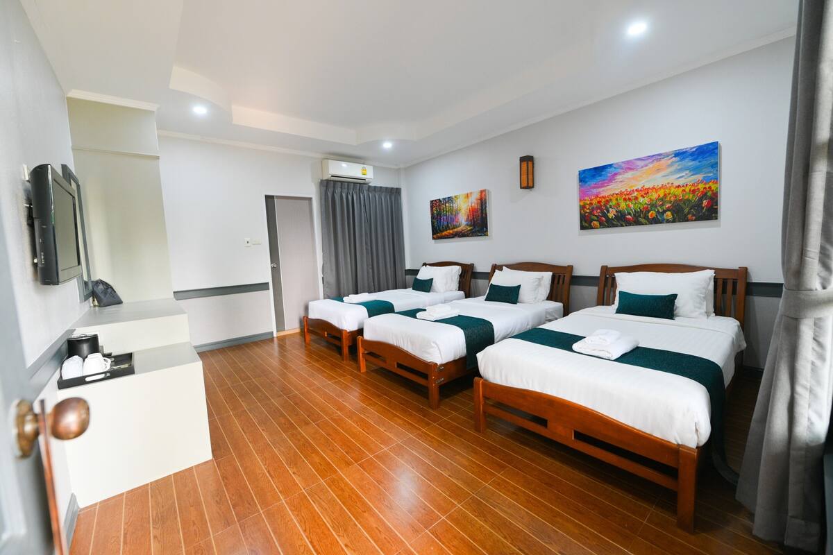 A hotel room with four beds, a desk, and a TV.