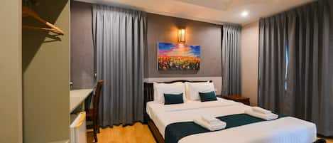 Habitación de hotel con cama, escritorio, silla, un cuadro y cortinas.