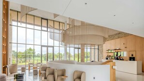 A spacious lobby with a curved reception desk, multiple seating areas, and large windows offering a view of the outdoors. - Apartment in Baillargues Near Golf Course (Baillargues)
