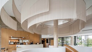 A modern interior with a central circular seating area, a reception desk, and a staircase. - Apartment in Baillargues Near Golf Course (Baillargues)