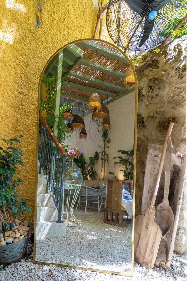 A mirror reflecting a staircase, a wooden bench, and a fan in a rustic setting.