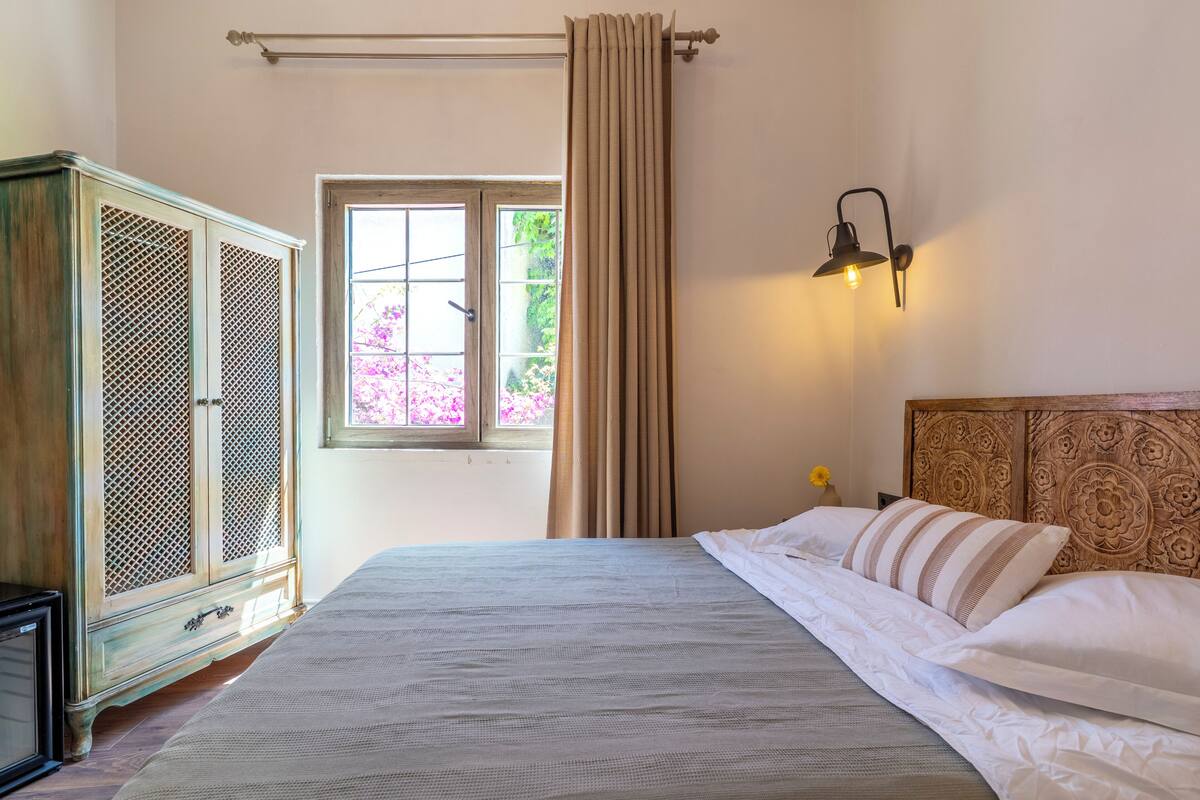 Un dormitorio con cama, armario, ventana con cortinas y lámpara de pared.