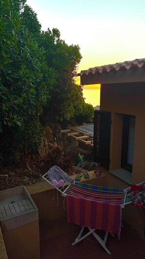 A patio area with a hammock, a drying rack, and a view of the sea at sunset.