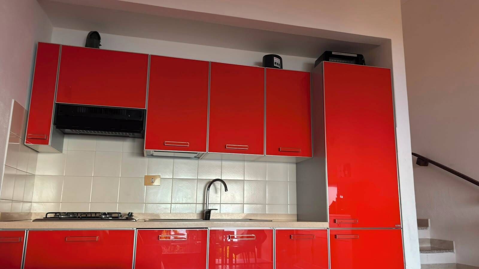 Cocina con armarios rojos, estufa a gas y grifo negro.
