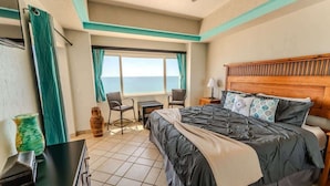 Een hotelkamer met een bed, een bureau, een stoel, een raam met uitzicht en een plafondventilator.