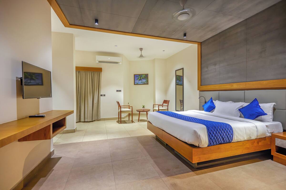 Une chambre d’hôtel comprenant un lit, un bureau, une chaise, une petite table et un téléviseur.