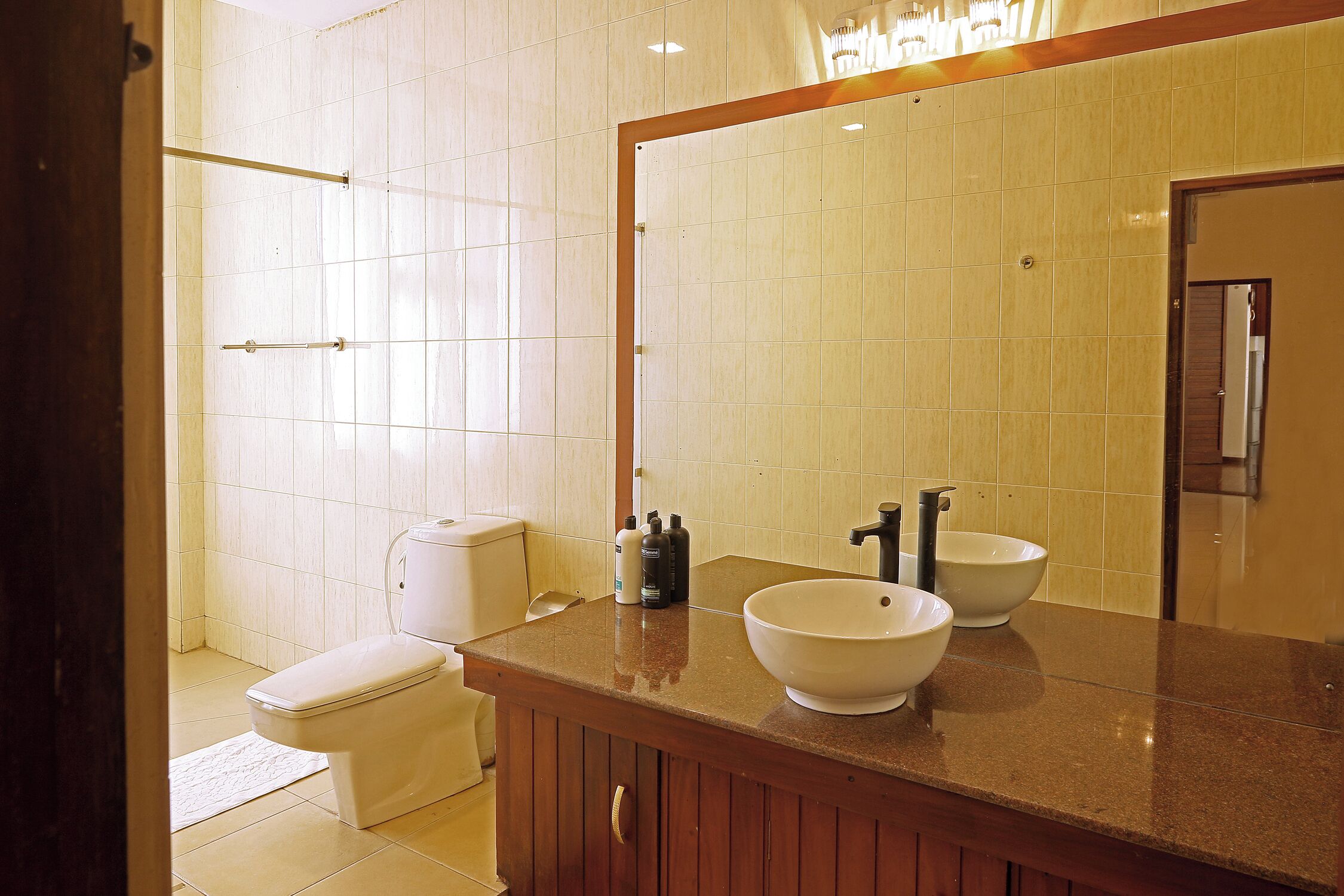 A bathroom with a toilet, a sink with a large mirror, and a shower area.