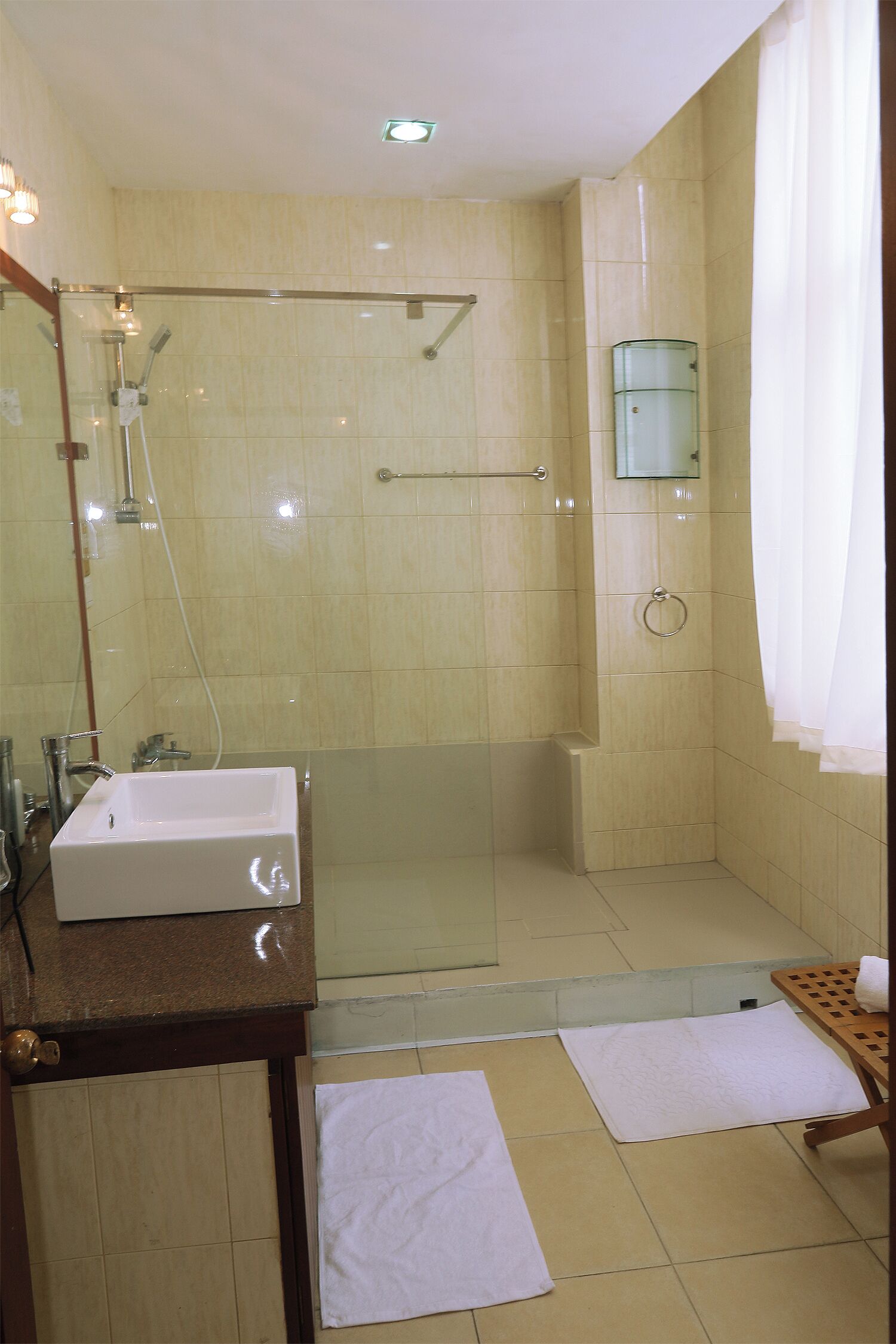Un baño con ducha envuelta en vidrio, un lavamanos y un espejo.