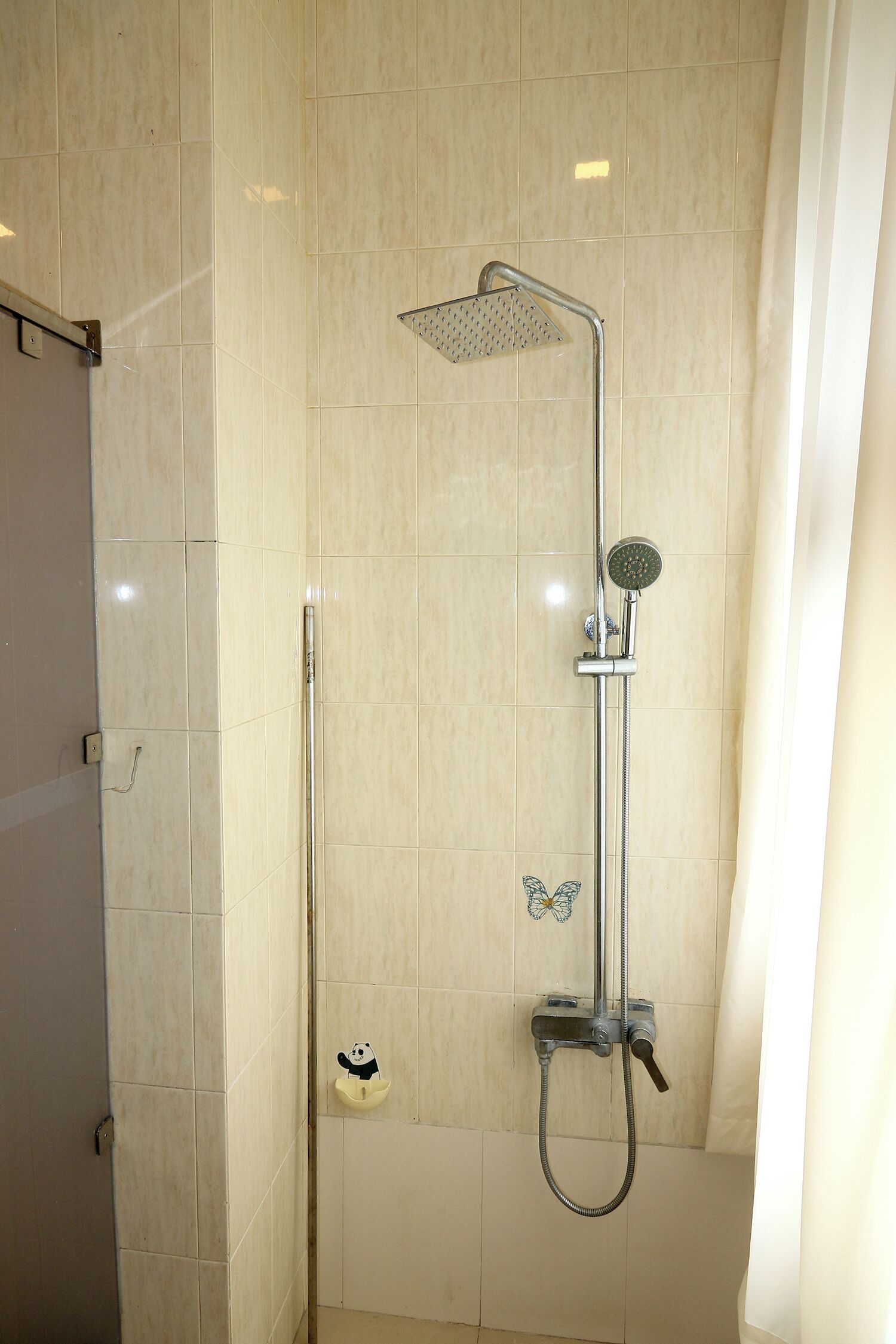 A shower with a handheld showerhead and a wall-mounted rain showerhead.