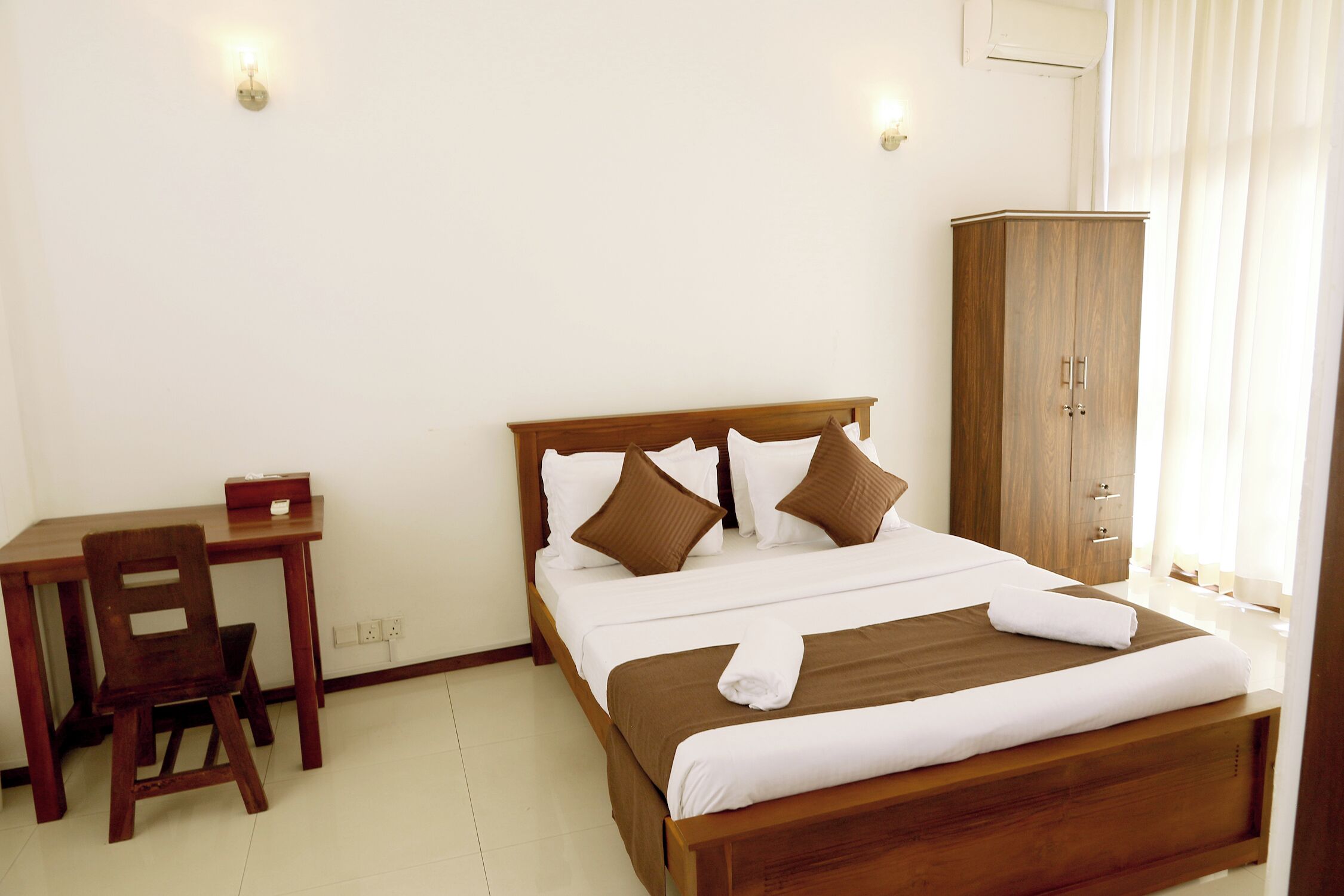 A bedroom with a wooden bed, a desk, and a chair.