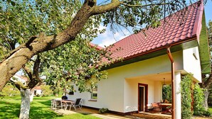 A house with a red-tiled roof, a covered patio, and a lawn. - Large Holiday Home With a Beautiful Garden (Slawno)
