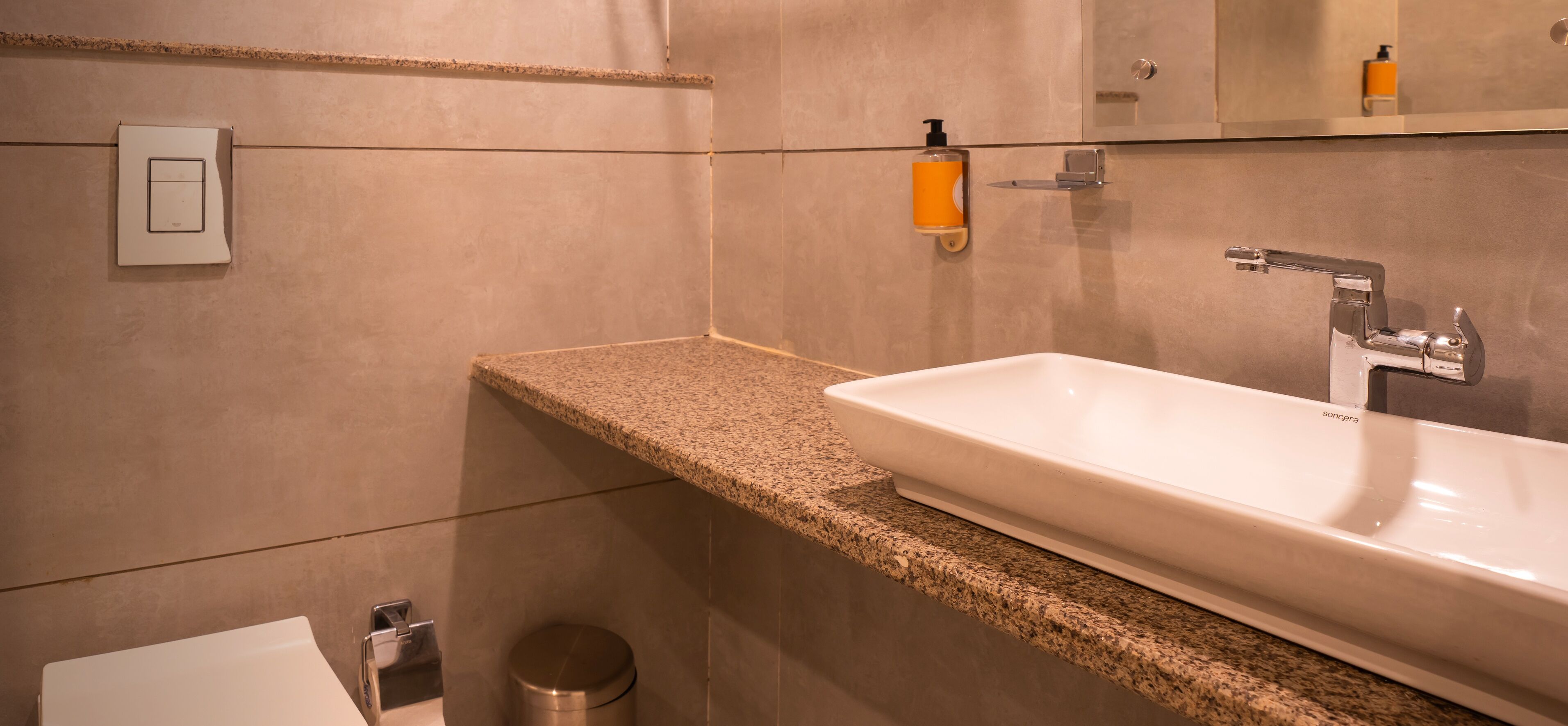Une salle de bain moderne avec un comptoir en granit, un lavabo blanc et un miroir.