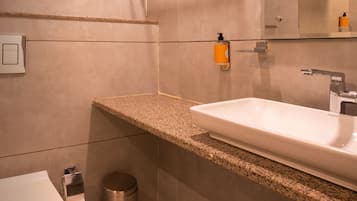 Une salle de bain moderne avec un comptoir en granit, un lavabo blanc et un miroir.