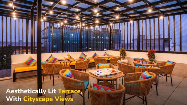 Una terraza con iluminación atractiva y vistas a la ciudad, con mobiliario de mimbre y techo de cristal.