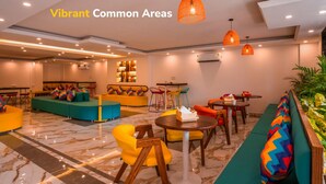 Un área de lounge moderna con asientos vibrantes, incluyendo sofás y sillones, y una mesa redonda central.