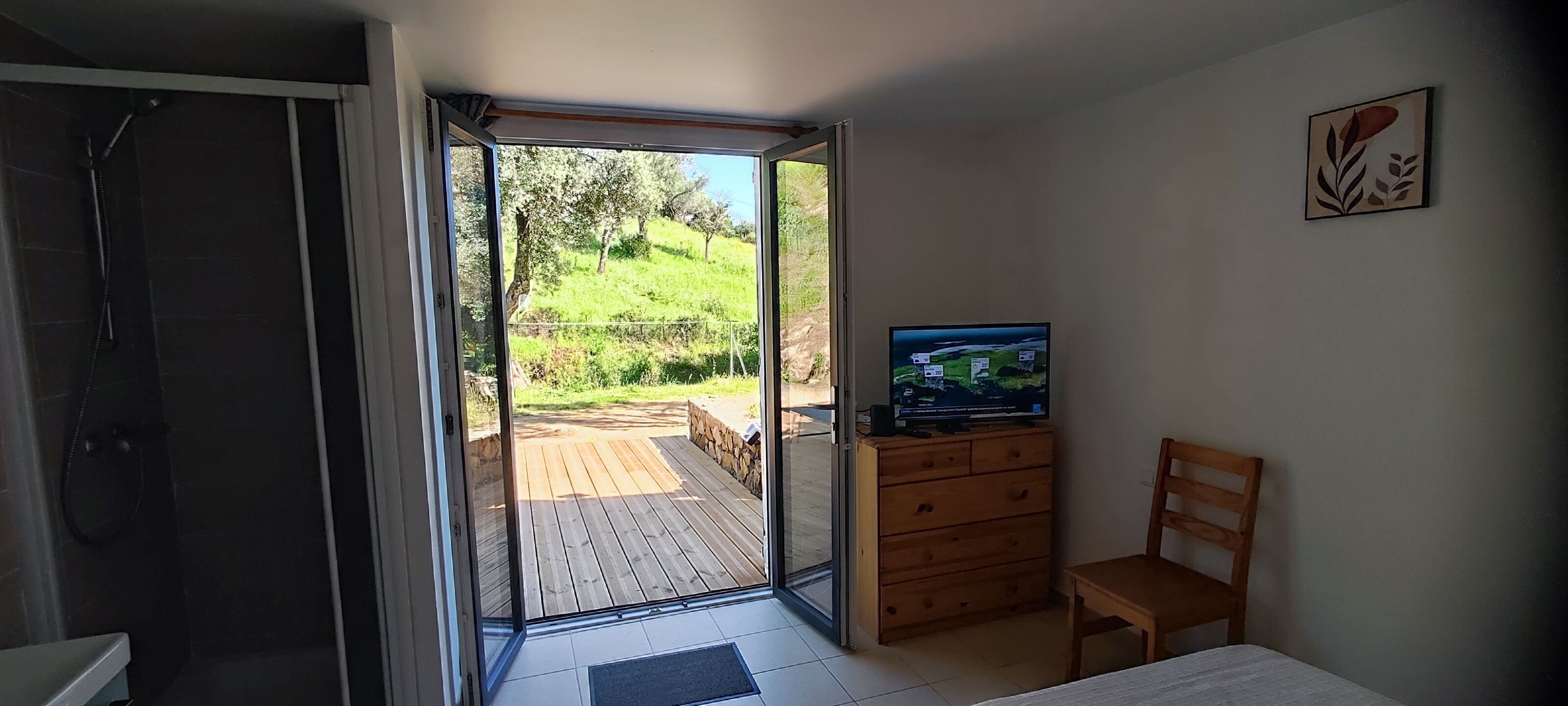 Une chambre avec une douche, un bureau en bois, une chaise et un téléviseur.