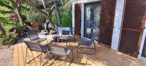 Une terrasse extérieure avec un plancher en bois, une table avec des chaises et un petit coin salon agrémenté de coussins.