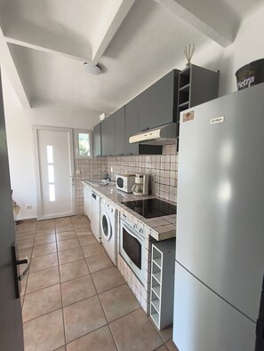A compact kitchen with a washing machine, a microwave, and a refrigerator.