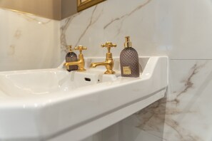 A bathroom sink with gold faucets and a hand lotion bottle. - Nelly Daly's Barn - Sleeps 6 - Brand New - Parking (Newry)